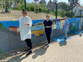 Von Schülern mit bunten Motiven bemalte Außenmauer umgrenzt unseren freundlichen Garten - Diakonie Hospiz Woltersdorf