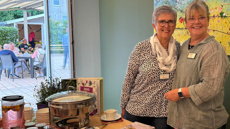 Zwei Mitarbeiterinnen stehen an einem Tisch mit Essen Zwei Mitarbeiterinnen stehen an einem Tisch mit Essen