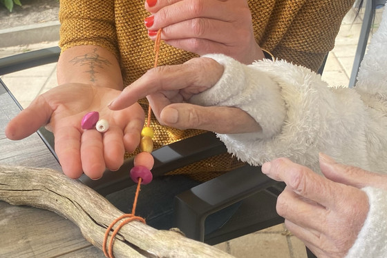 Gast fädelt Holzperlen auf - Kunsttherapie - Diakonie Hospiz Woltersdorf