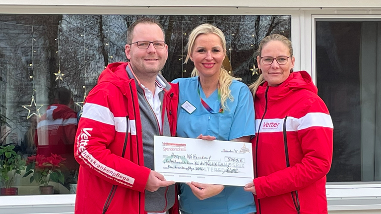 Hospiz-Mitarbeiterin (Mitte) nimmt Spendenscheck von der Hauskrankenpflege Vetter entgegen