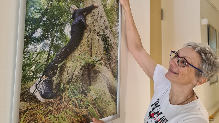 Frau hängt ein Bild im Flur des Diakonie Hospiz Wannsee auf