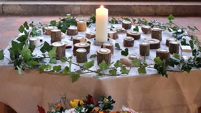 Kerzentisch der Gedenkfeier des Diakonie Hospiz Woltersdorf mit zentraler Kerze, Holz-Teelichtern und Efeukranz zum Gedenken an die verstorbenen Gäste