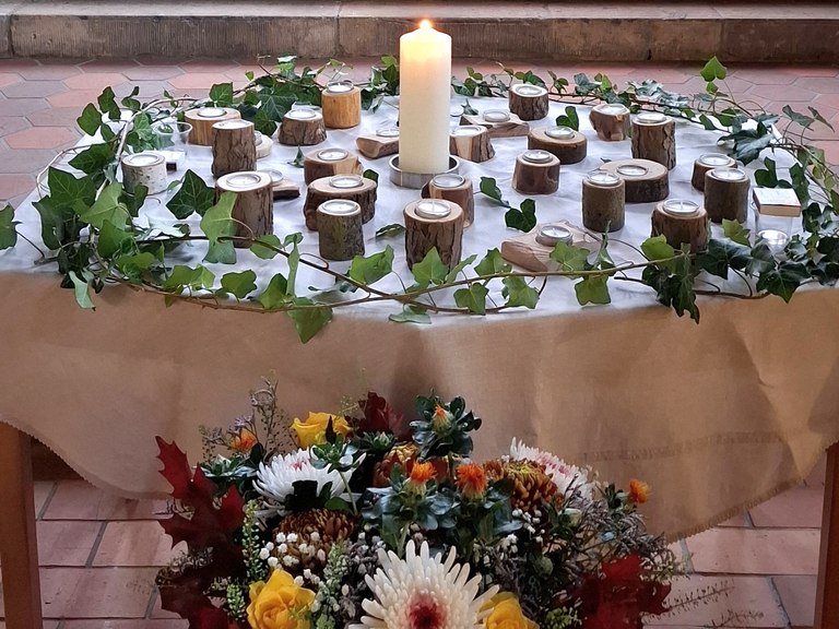 Kerzentisch der Gedenkfeier des Diakonie Hospiz Woltersdorf mit zentraler Kerze, Holz-Teelichtern und Efeukranz zum Gedenken an die verstorbenen Gäste