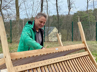 Ein ehrenamtlich engagierte Mann arbeitet an einer Sitzbank aus Holz im Garten des Diakonie Hospiz Woltersdorf.