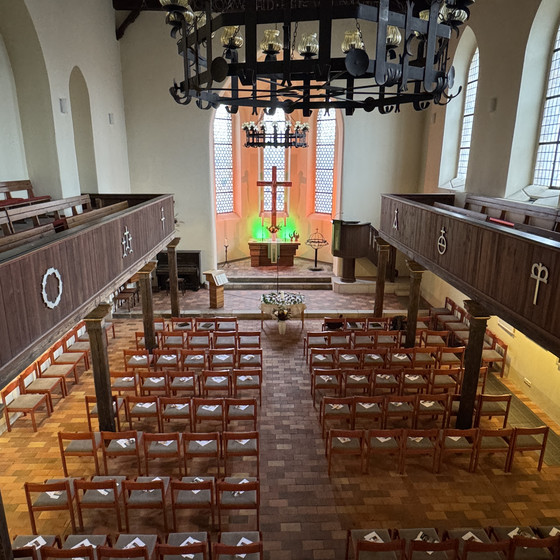 Blick von der Empore auf die bestuhlte St.-Michael-Kirche Woltersdorf zur Gedenkfeier des Diakonie Hospiz Woltersdorf, mit vorbereiteten Sitzreihen und beleuchtetem Altarraum