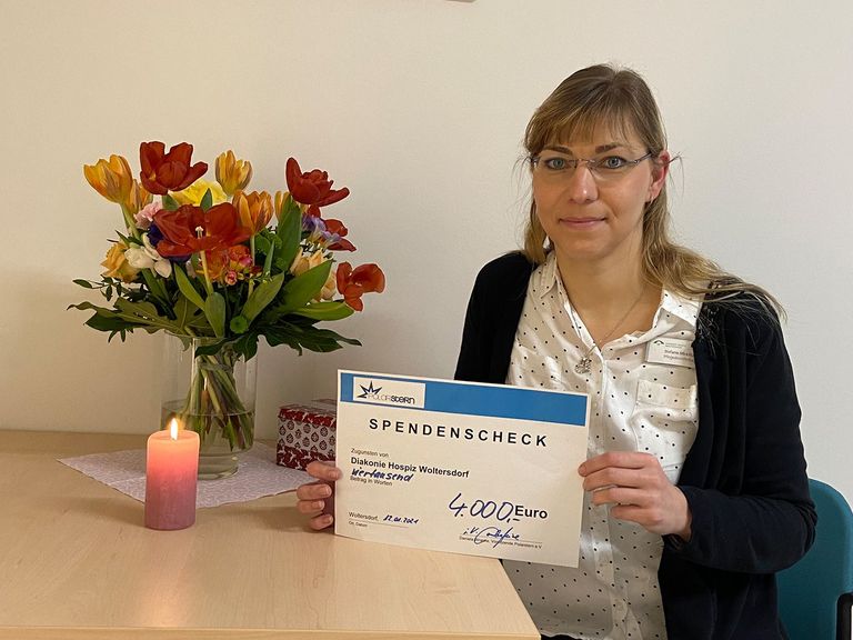 Diakonie Hospiz Woltersdorf - Pflegedienstleitung Stefanie Micklitza hält Spendenscheck von Förderverein Polarstern in der Hand