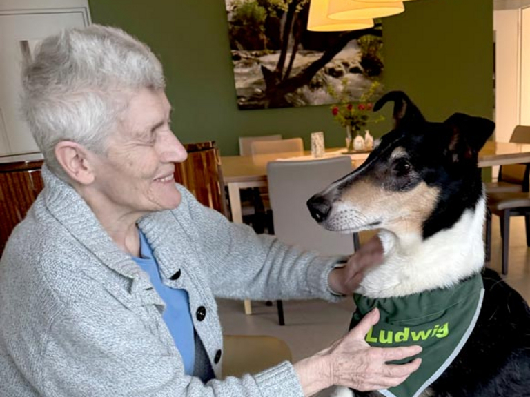 Hospizgast streichelt einen Therapiehund im Diakonie Hospiz Woltersdorf