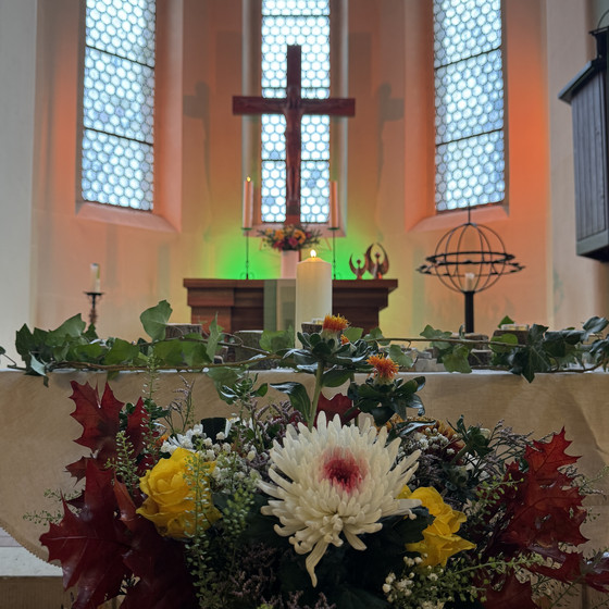 Altarraum der St.-Michael-Kirche Woltersdorf während der Gedenkfeier des Diakonie Hospiz Woltersdorf, mit Kreuz, Kerzen und herbstlichem Blumenschmuck für die verstorbenen Gäste