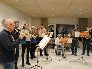 Ehrenamtlich engagierte Menschen spielen in einem Bläserchor mit verschiedenen Instrumenten ein Konzert im Eingangsfoyer im Diakonie Hospiz Woltersdorf.